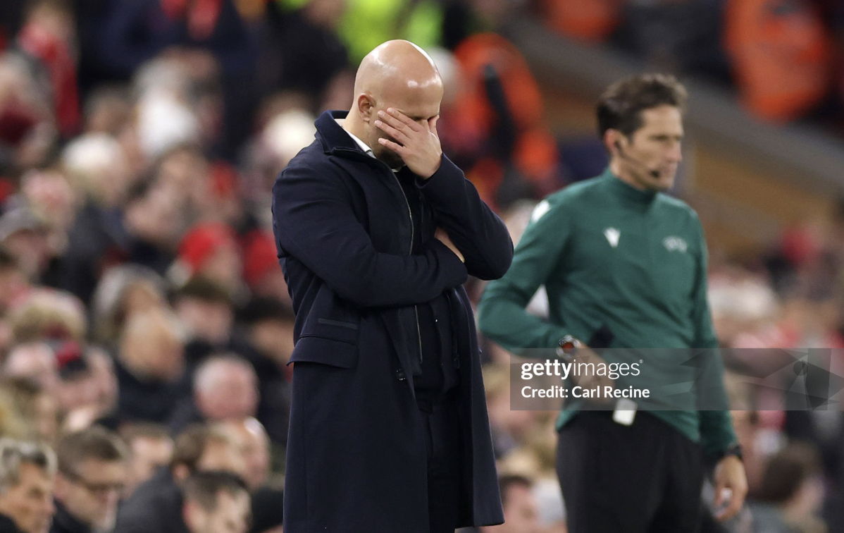Arne Slot covering his face on the touchline during a Liverpool match.